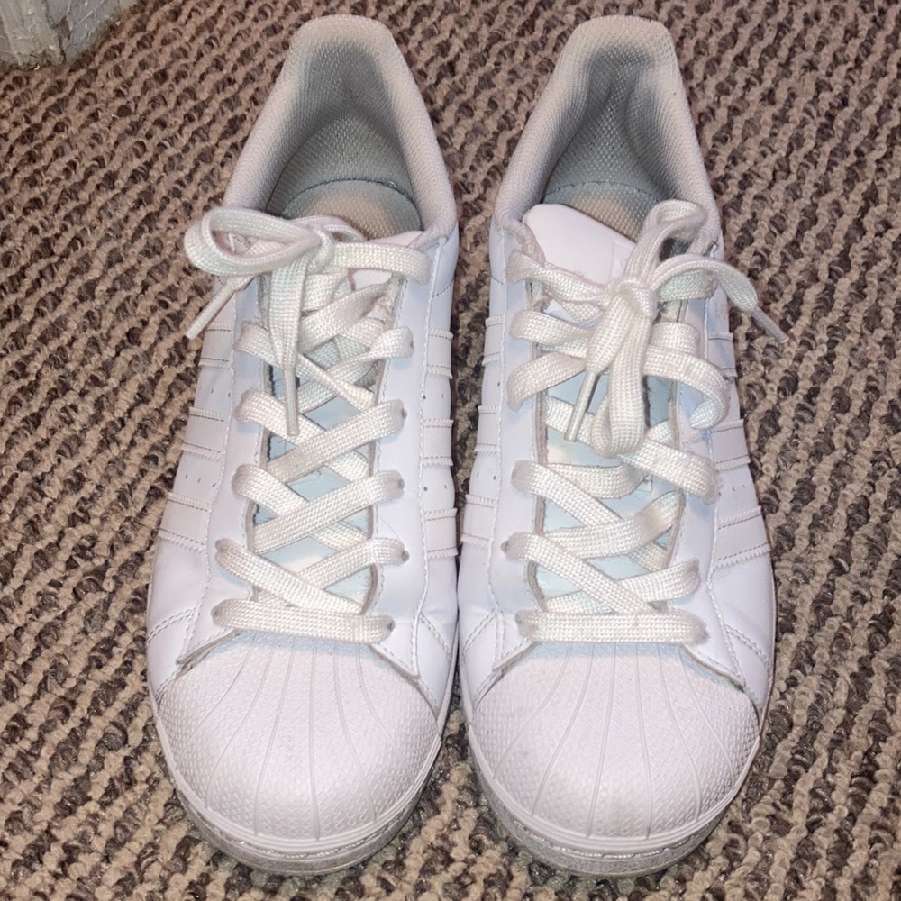 All white Adidas Superstar sneakers